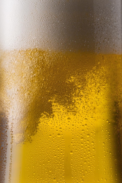 Un vaso de cerveza dorada fría con gotas de condensación y espuma. Tomada en estudio con una 5D mark III.