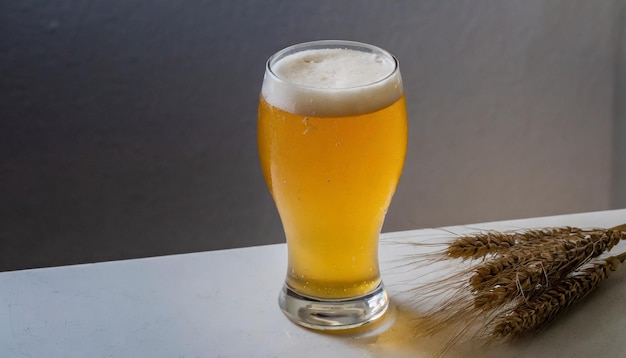 vaso de cerveza y espigas de trigo en la mesa sobre un fondo gris