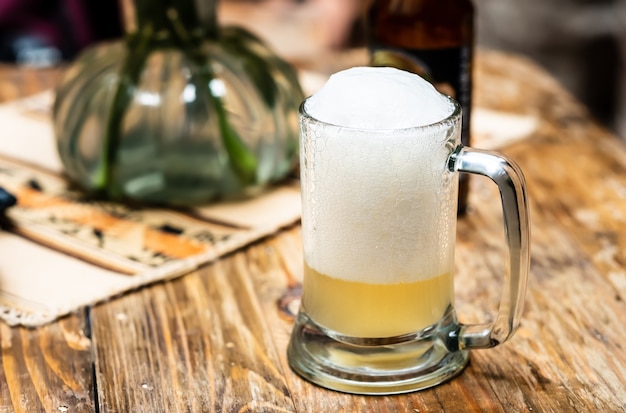 Foto vaso de cerveza con espuma sobre la mesa de madera