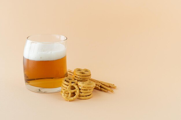 Vaso de cerveza espumosa refrescante con pretzel sobre fondo amarillo Espacio para copiar