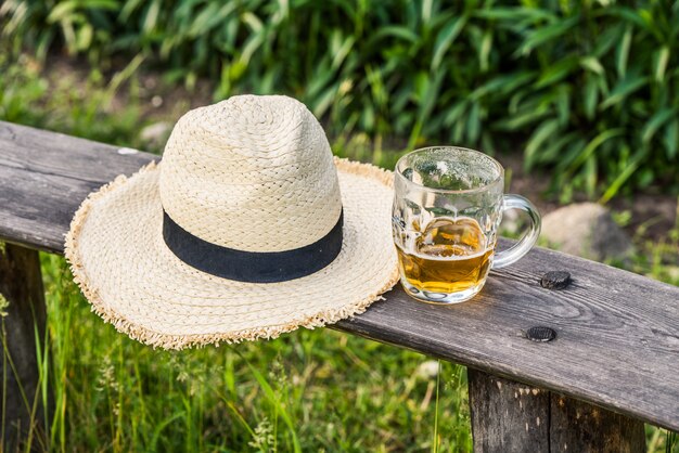 Vaso de cerveza ligera con gorro de tejer en el banco