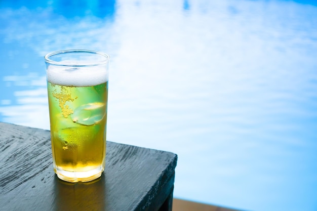 Vaso de cerveza ligera en la mesa de madera en la piscina