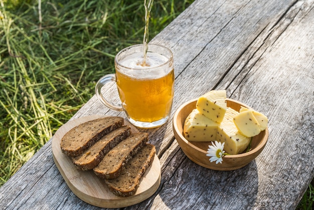 Vaso de cerveza ligera con queso y pan de centeno.