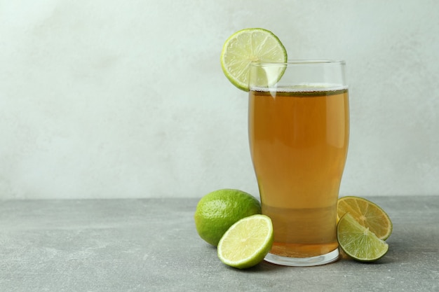 Vaso de cerveza y limas contra textura blanca