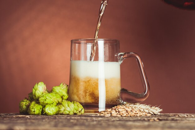 Vaso de cerveza con lúpulo y cebada en la mesa de madera