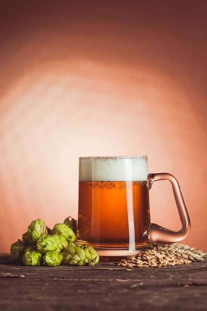 Vaso de cerveza con lúpulo y cebada en la mesa de madera