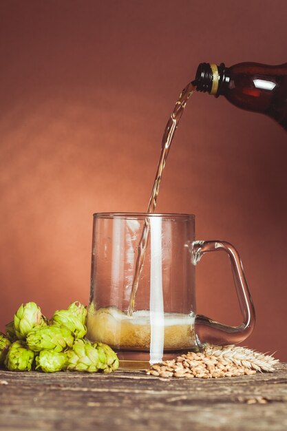 Vaso de cerveza con lúpulo y cebada en la mesa de madera