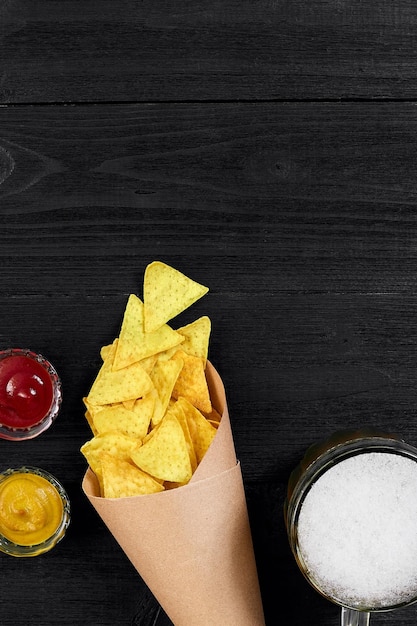 Vaso de cerveza con nachos chips sobre un fondo de madera