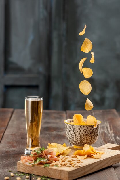 El vaso de cerveza y papas fritas, pistachos aislado en un blanco