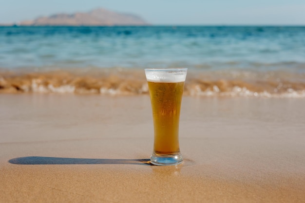 Vaso de cerveza en la playa un vaso de cerveza con fondo de mar