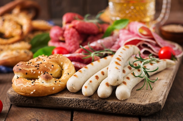 Vaso de cerveza, pretzels y diversas salchichas Oktoberfest.