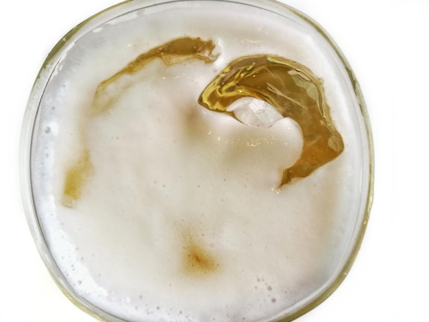 Vaso de cerveza en primer plano con burbujas de cerveza y hielo en fondo blanco vista superior