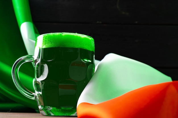 Vaso de cerveza verde contra la bandera de Irlanda cerrar