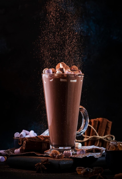 Vaso de chocolate caliente bebida de cacao espolvoreado con cacao en polvo Fondo oscuro Concepto de comida y bebida de invierno con espacio de copia