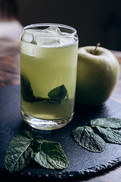 Un vaso de cóctel de julepe de menta con una manzana verde sobre una mesa.