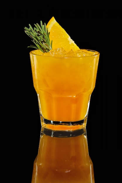 Vaso con cóctel de naranja con reflejo.