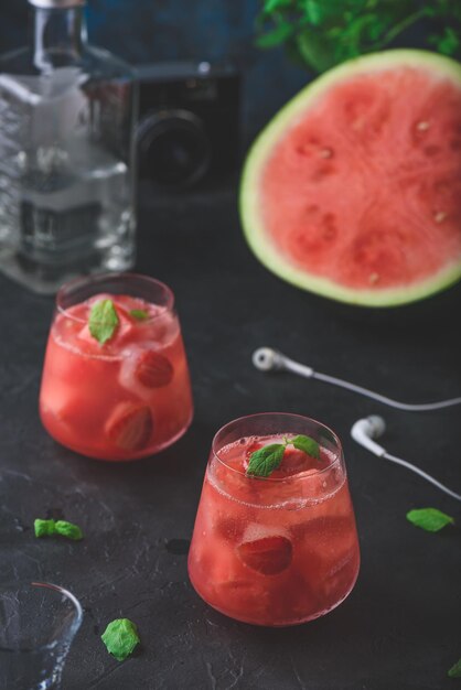 Vaso de coctel de sandía y fresa con guarnición de menta sobre un fondo de hormigón oscuro