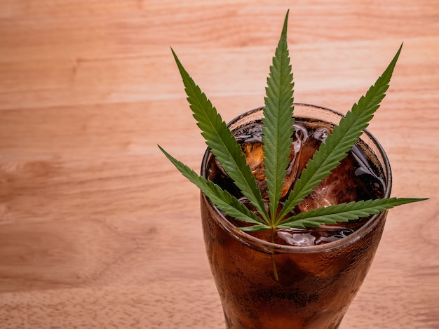 de cola con de hielo y hojas de cannabis sobre la mesa de | Foto Premium