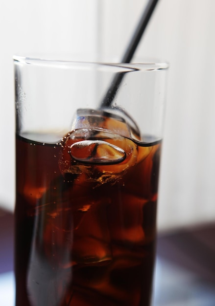 Foto vaso de cola con cubitos de hielo en la mesa