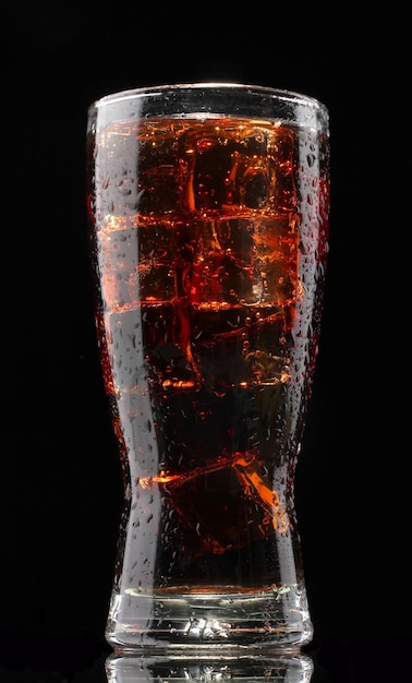 Vaso de cola con hielo sobre fondo negro