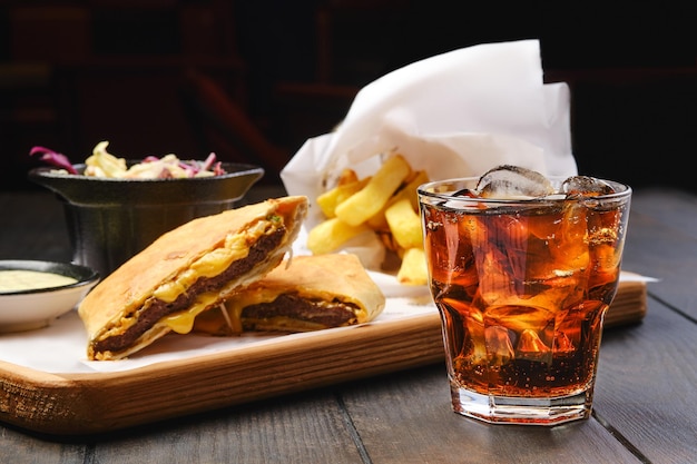 Vaso de cola con hielo con tortilla y patata frita en el fondo se centran en primer plano