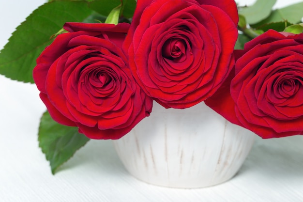 Vaso com buquê de flores de rosas vermelhas em madeira branca