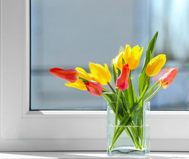 Vaso com lindas tulipas no peitoril da janela