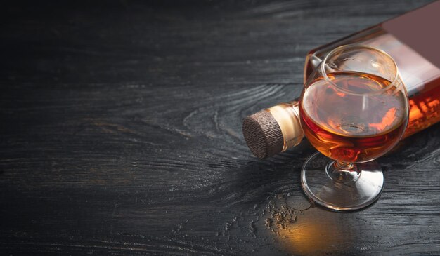 Foto vaso de coñac y botella sobre el fondo oscuro