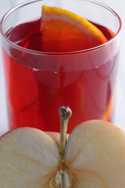 El vaso contiene sangría. Frente a él se encuentra una manzana cortada.