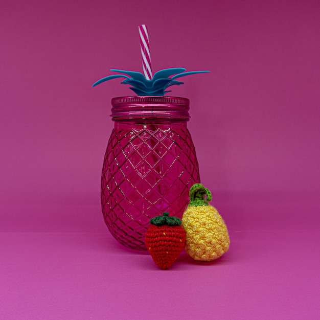 Vaso de cristal, piña rosa con tapa de metal y plástico plateado, con fruta amigurumi.