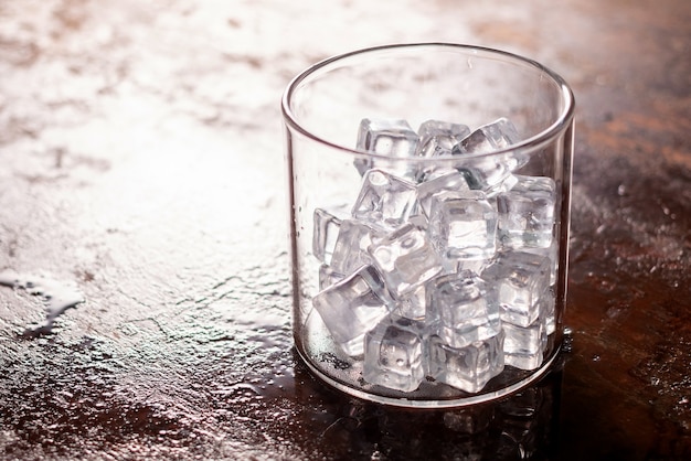 Vaso de cubo de hielo en la mesa de madera y la luz de fondo borroso