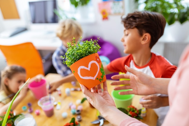 Vaso de flores com foto. Foto de um professor segurando um vaso de laranja com uma bela foto, perto dos alunos