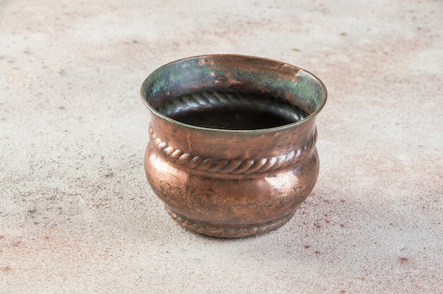 Vaso de flores de cobre antigo no chão de concreto