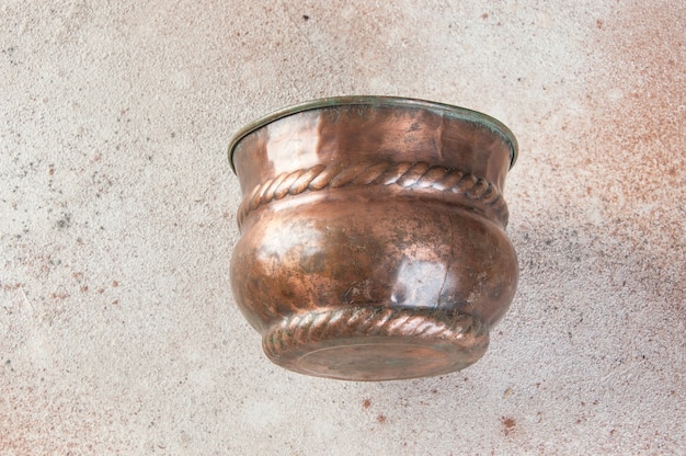 Vaso de flores de cobre antigo no chão de concreto