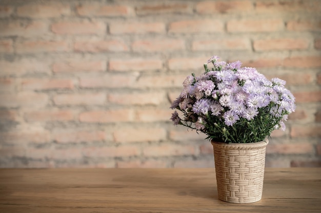 Vaso de flores na mesa com um fundo de parede de tijolos.