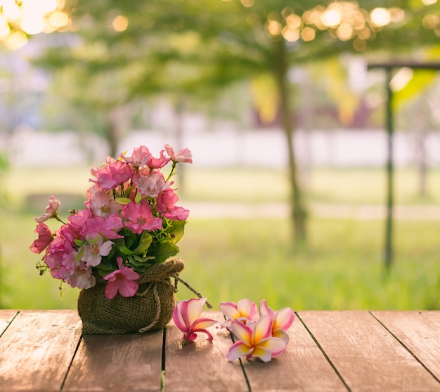 vaso de flores na mesa de madeira com vista para o jardim