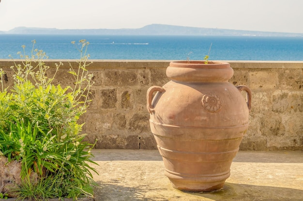 Vaso de terracota antigo contra um panorama mediterrâneo Itália