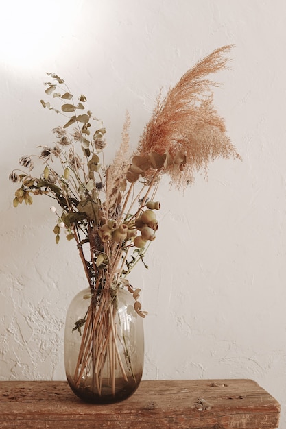 Vaso de vidro com plantas secas na parede branca Decoração minimalista para casa