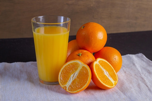 Vaso de zumo de naranja y naranjas en una mesa