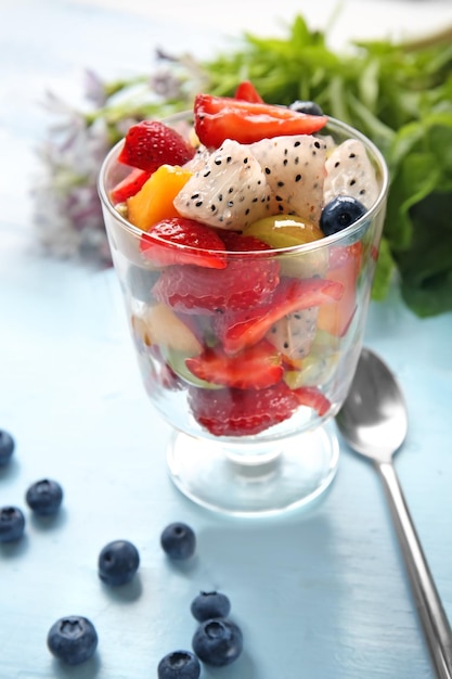 Vaso con deliciosa ensalada de frutas en la mesa