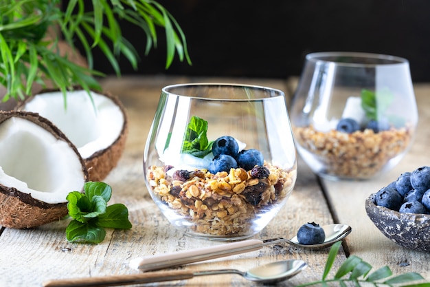 Un vaso de desayuno saludable: granola con arándanos frescos, chips de coco y menta