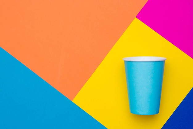 Vaso desechable de papel azul sobre fondo multicolor hermoso