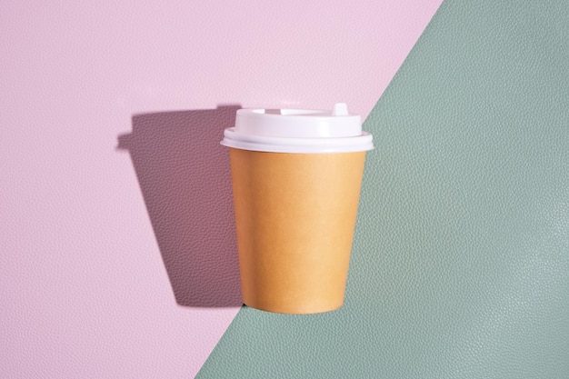 Vaso desechable de papel para café y té caliente sobre un fondo verde rosa. Concepto y tendencia de comida para llevar.