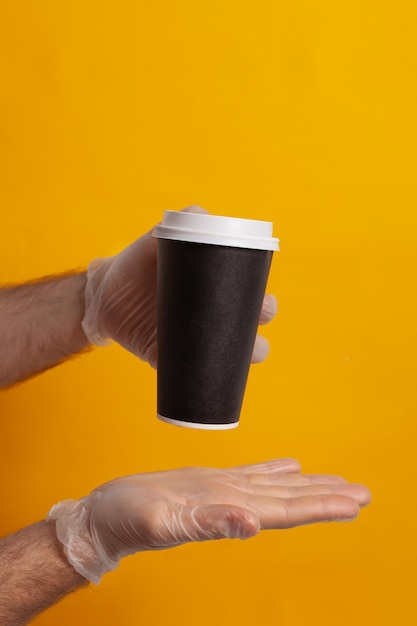 Vaso desechable sujetado por una mano con guante de protección