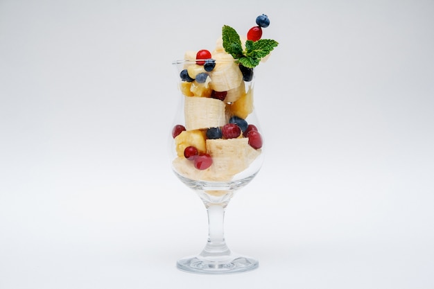 Vaso de ensalada de frutas aislado sobre fondo blanco.