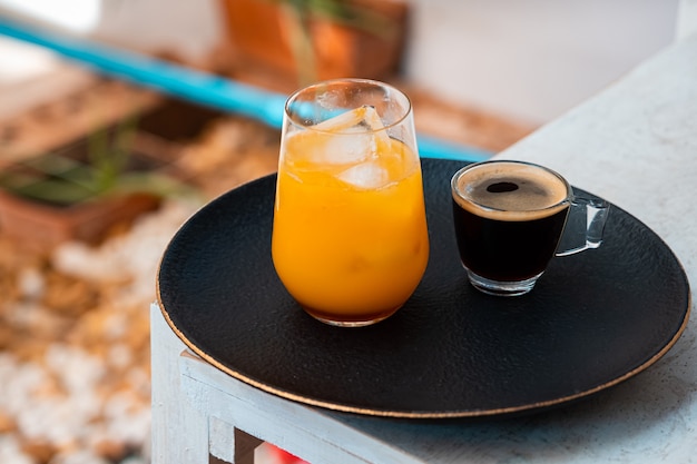 Vaso de espresso con jugo de naranja en la mesa de madera