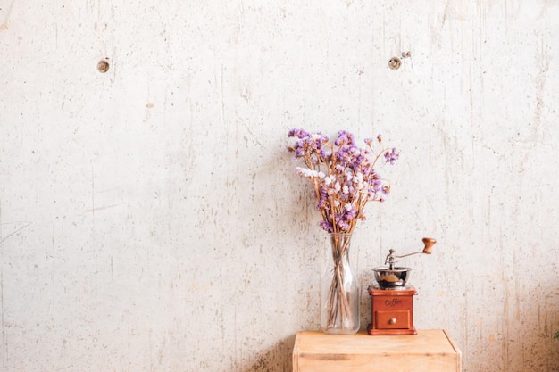 Vaso de flores y molinillo de café contra la pared