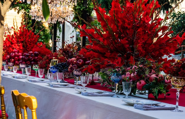 Vaso de flores rojas en la mesa contra árboles y plantas