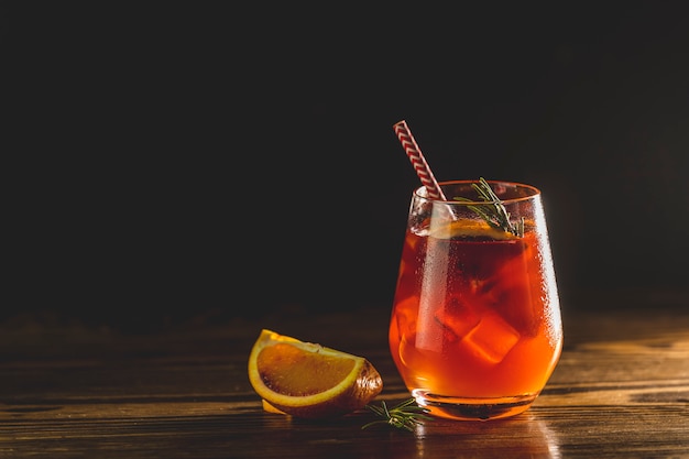 Vaso con gotas de agua de cóctel italiano aperol spritz con rodajas de naranja, hielo y minton mesa de madera oscura con luz de fondo increíble. Cóctel alcohólico Milano Spritzer