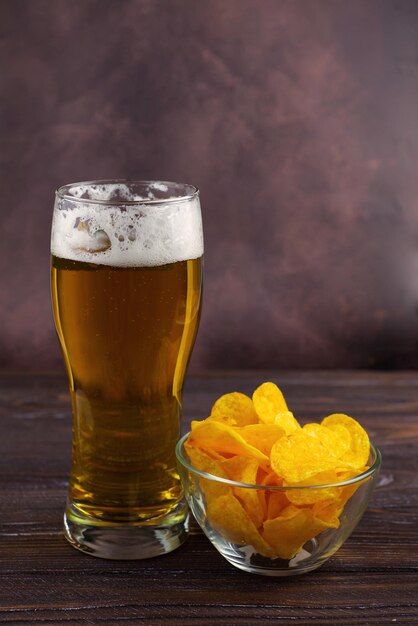 un vaso grande de cerveza ligera fría con espuma en un fondo oscuro Día de San Patricio